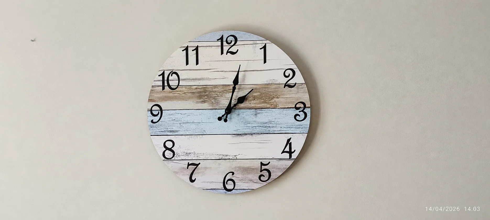 Grande horloge murale en planches de bois peintes dans le séjour du gîte Jardin.