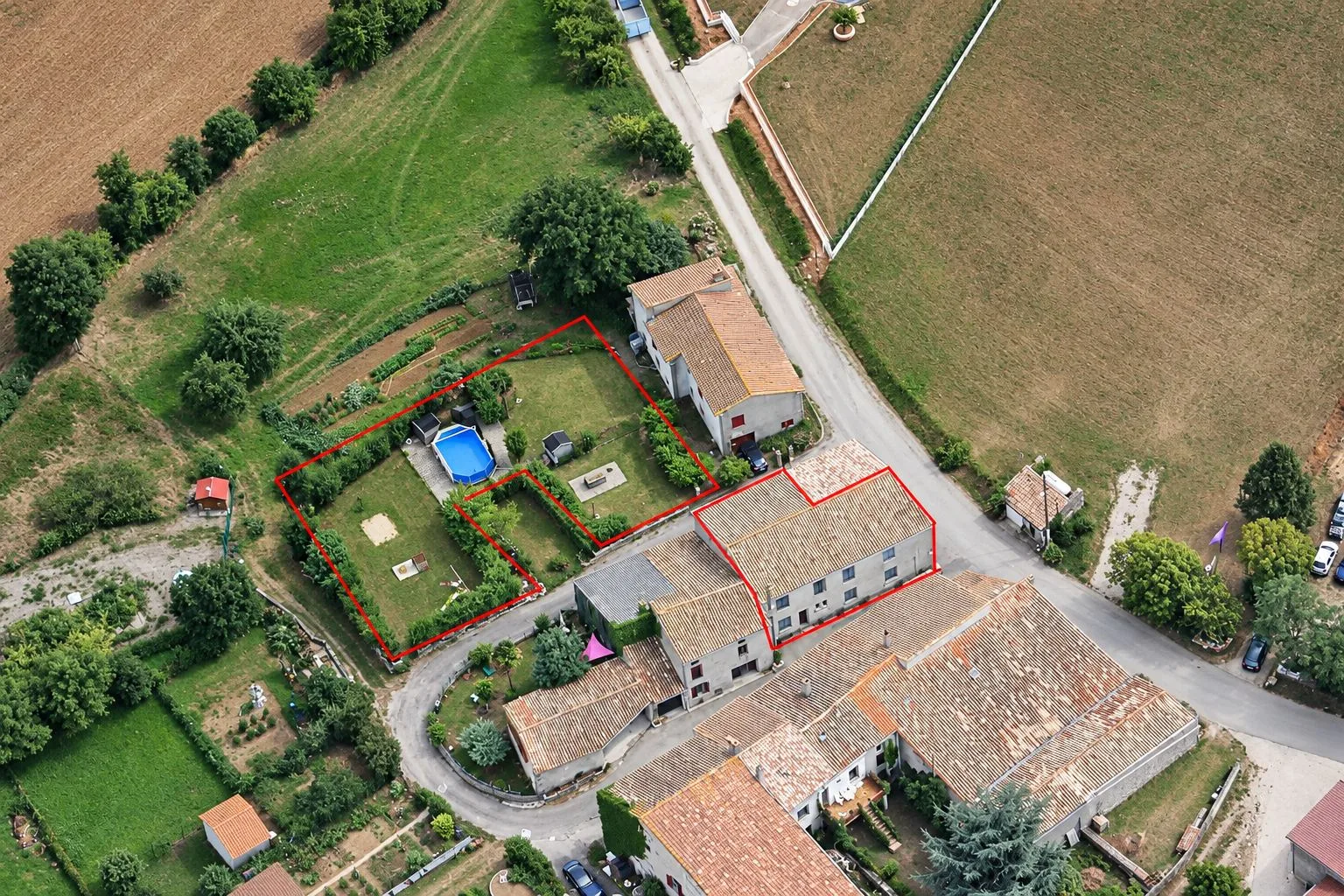 Vue aérienne du hameau de Campserdou : toits de tuiles, jardin et piscine, avec la propriété entourée d'un trait rouge.
