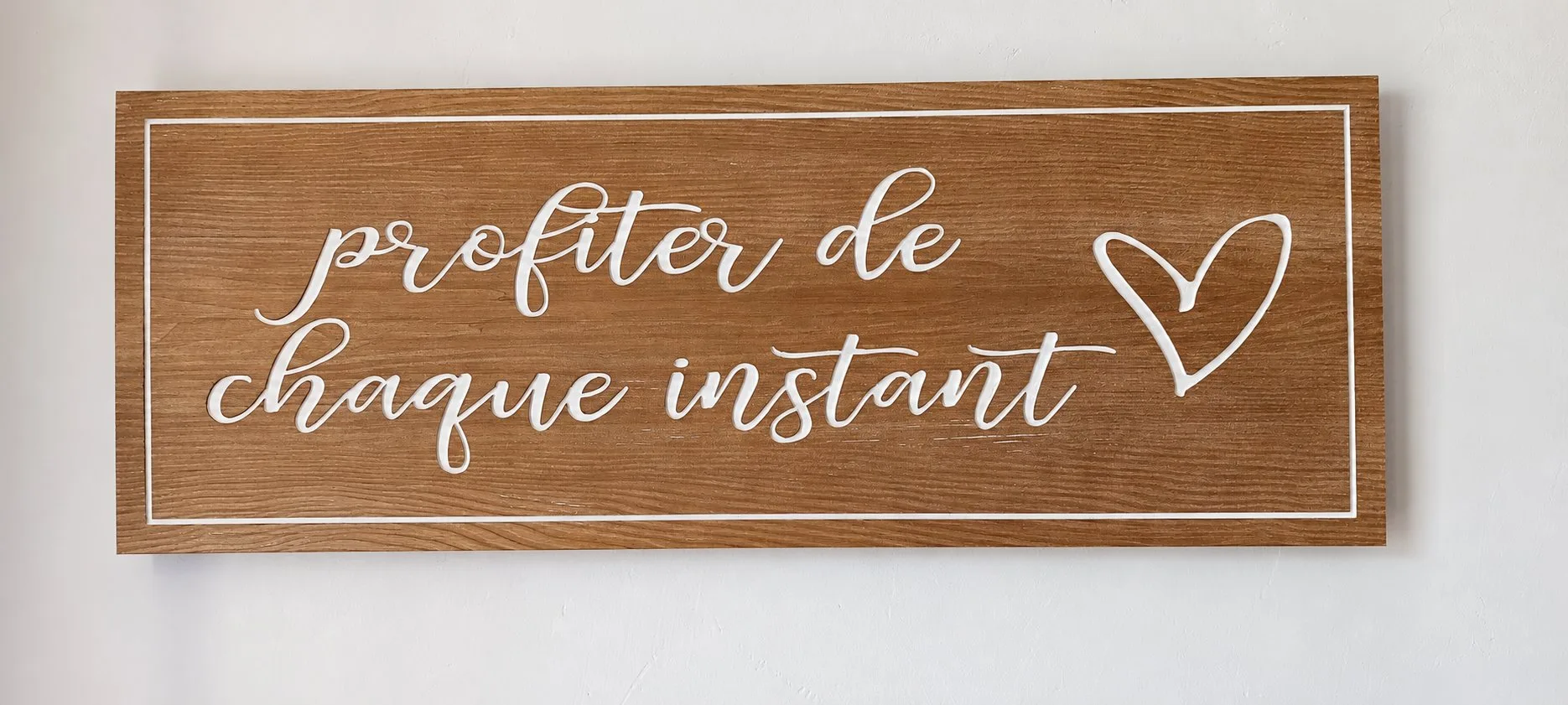 Panneau en bois clair portant l'inscription « profiter de chaque instant » et un cœur.